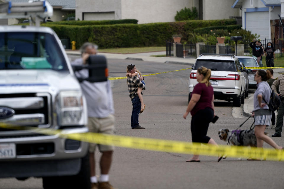 Neighbors watch fire crews near the scene of a small plane crash, Monday, Oct. 11, 2021, in Santee, Calif. At least two people were killed and two others were injured when the plane crashed into a suburban Southern California neighborhood, setting two homes ablaze, authorities said. (AP Photo/Gregory Bull)