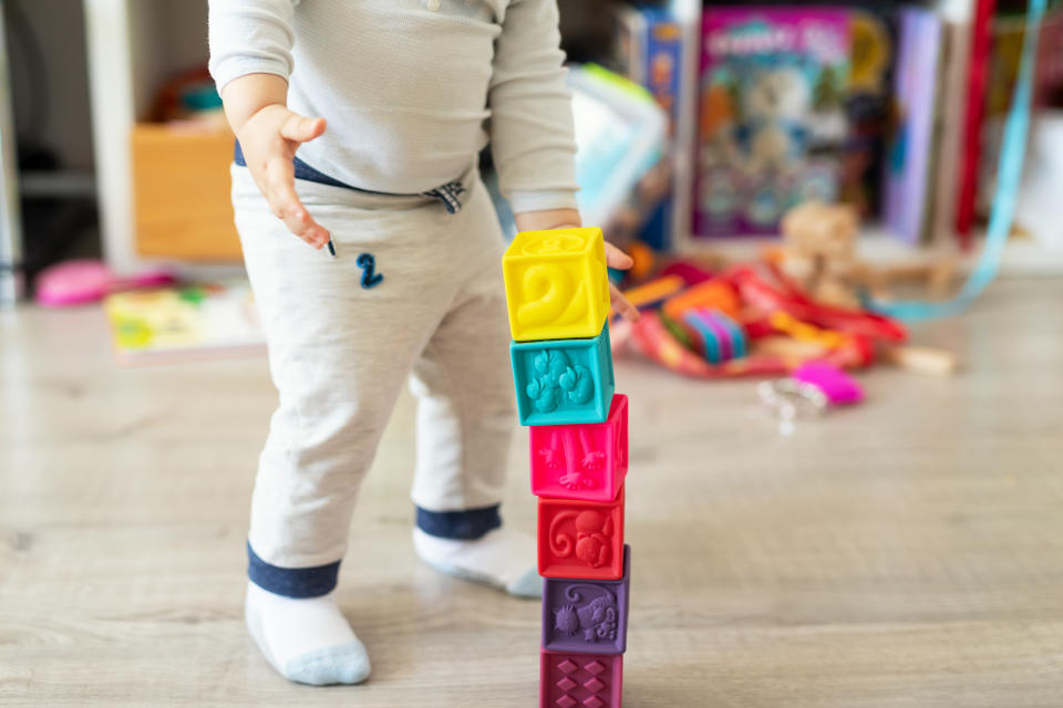 Cute adorable caucasian baby boy playing colorful toys at home. Happy child having fun building tower of soft rubber cubes. Children development and hapy chilldhood concept.