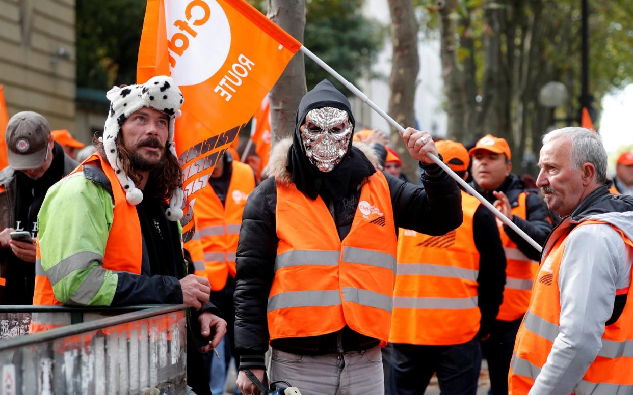 A masked demonstrator holds a flag of the French Democratic Confederation of Labour union (CFDT) in Paris during a national protest of lorry drivers against the government's labour reforms - REUTERS