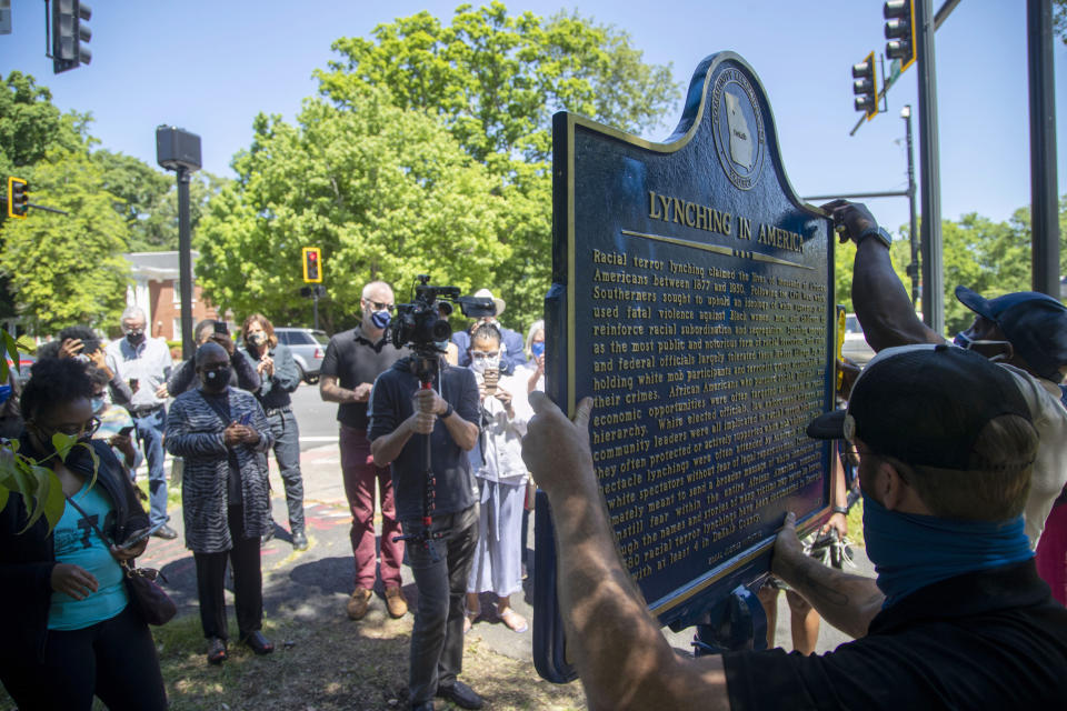 People gather to watch the installation of a historical marker that tells the story of the lynching of Porter Flournoy Turner in Atlanta's Druid Hills community, Thursday, May 6, 2021. Porter Turner was lynched near the area in August 1945. (Alyssa Pointer/Atlanta Journal-Constitution via AP)