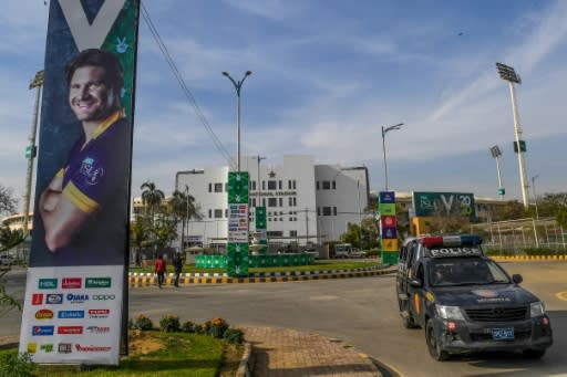 A police vehicle guards the National Stadium in Karachi alongside a poster of Australian star Shane Watson ahead of the Pakistan Super League season ebinning Thursday