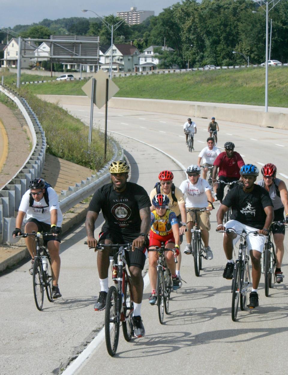 LeBron James, second from left, rides along the Akron Innerbelt during the King for Kids Bikeathon in 2009. The high-rise in the skyline is the Spring Hill Apartment complex where James and his mother, Gloria, lived until his high school graduation.