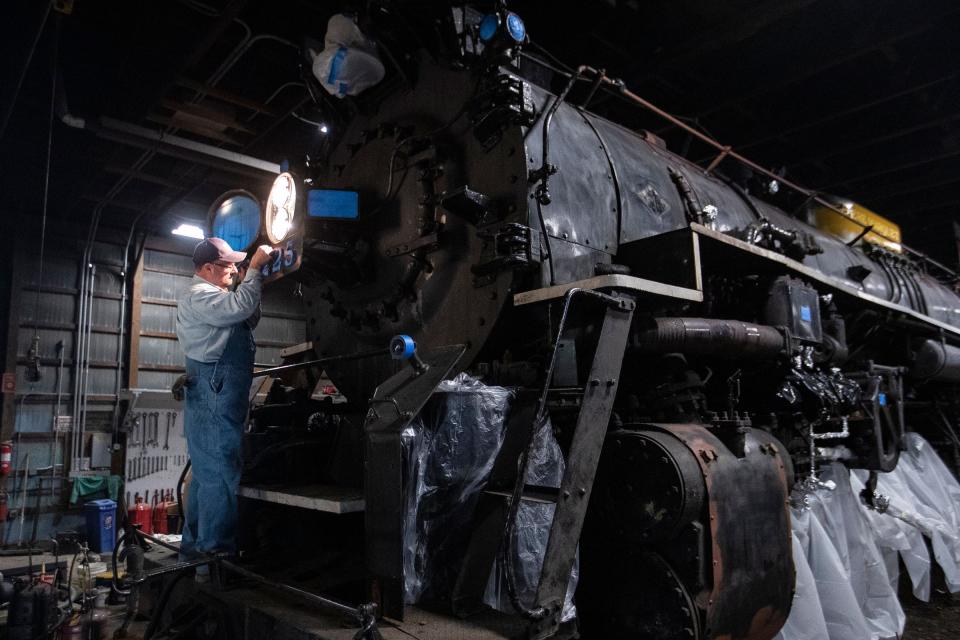 Volunteer Jeff Rayner puts masking tape on the front of Pere Marquette 1225 before a new paint job as they get ready for the first day of the North Pole Express at the Steam Railroading Institute in Owosso on Thursday, Nov. 16, 2023.