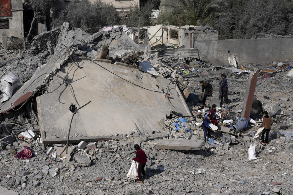 Palestinians salvage belongings from the rubble of a building of the Hamad family destroyed in an Israeli strike in Deir al Balah, Gaza Strip, Friday, Dec. 29, 2023. (AP Photo/Adel Hana)