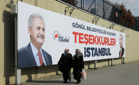 FILE PHOTO: People walk past by AK Party billboards with pictures of Turkish President Tayyip Erdogan and mayoral candidate Binali Yildirim in Istanbul, Turkey, April 1, 2019. The billboards read: " Thank you Istanbul ". REUTERS/Huseyin Aldemir/File Photo