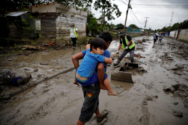 FILE PHOTO: A child carries his brother in a street covered in mud after the floods caused by the rains brought by Hurricanes Eta and Iota, in La Lima