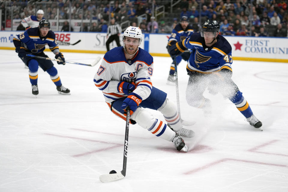 Edmonton Oilers' Connor McDavid (97) handles the puck as St. Louis Blues' Torey Krug (47) and Jake Neighbours (63) defend during the third period of an NHL hockey game Monday, April 1, 2024, in St. Louis. (AP Photo/Jeff Roberson)