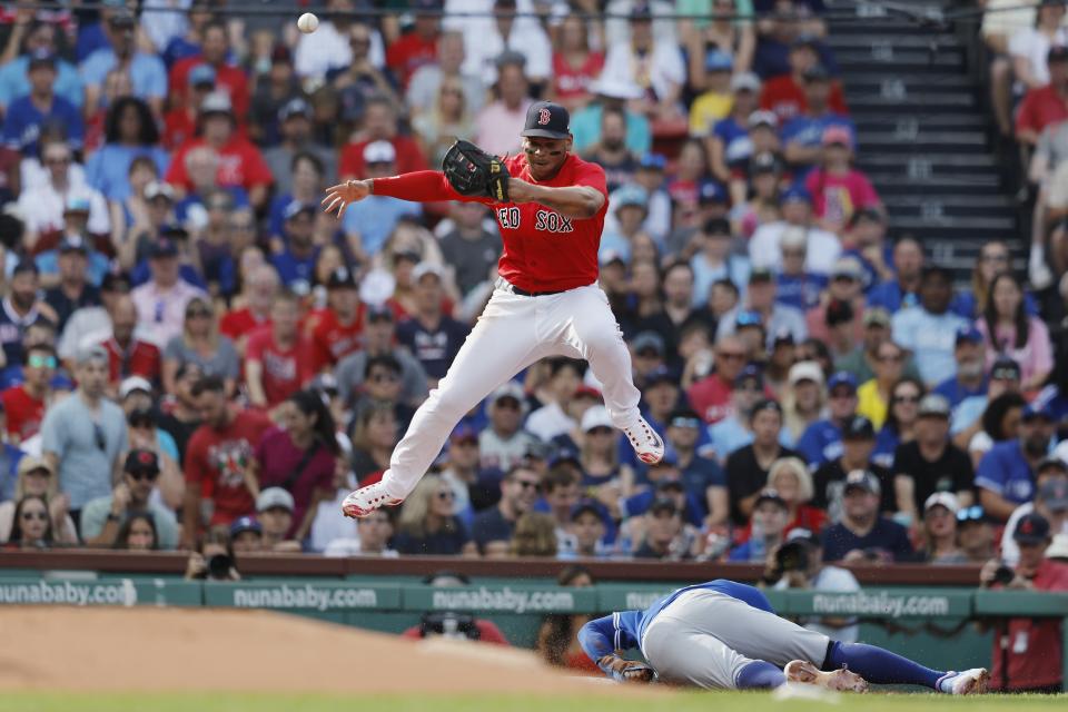 Toronto Blue Jays' George Springer steals third base under Boston Red Sox third baseman Rafael Devers on a high throw by catcher Connor Wong during the third inning of a baseball game, Saturday, Aug. 5, 2023, in Boston. (AP Photo/Michael Dwyer)