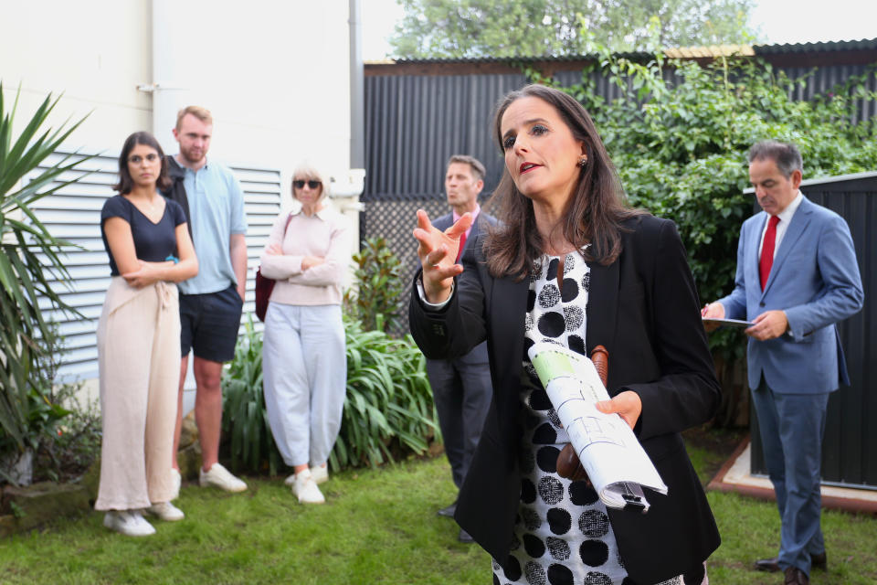 An Auctioneer counts down a bid for a residential property as would-be buyers look on.