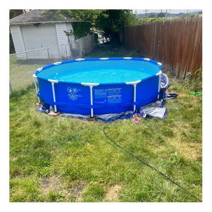 Above-ground pool in a backyard with a hose lying nearby. Ideal for family summer shopping