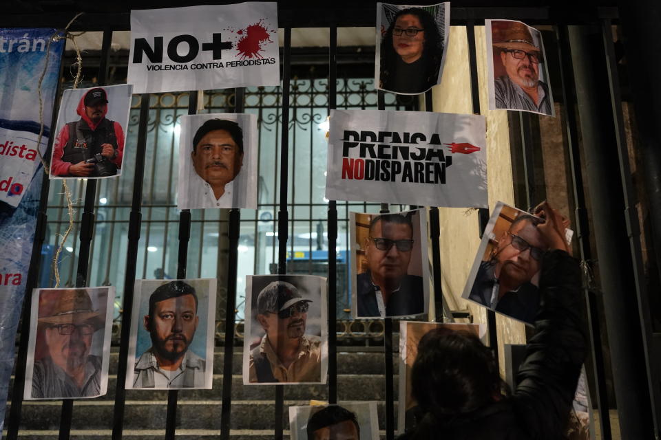 A woman posts photos of murdered journalists during a national protest against the murder of journalists Lourdes Maldonado and freelance photojournalist Margarito Martínez, in Mexico City, Tuesday, Jan. 25, 2022. Mexico's Interior Undersecretary Alejandro Encinas said recently that more than 90% of murders of journalists and rights defenders remain unresolved, despite a government system meant to protect them. (AP Photo/Eduardo Verdugo)