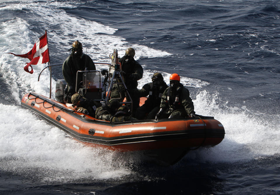 Finnish crew members of the quick response force and Danish personnel conduct a drill on a boat, wearing a protective mask and special uniforms, as part of the emergency drills on Danish warship Esbern Snare on the sea between Cyprus and Syria, Sunday, Jan. 5, 2014. Two cargo ships and their warship escorts set sail at waters near Syria where they will wait for orders on when they can head to the Syrian port of Latakia to pick up more than 1,000 tons of chemical agents. (AP Photo/Petros Karadjias)