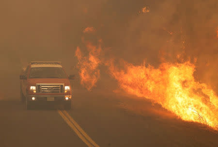 A firetruck rushes past flames that overran a road at the River Fire (Mendocino Complex) in Lakeport, California, U.S. July 31, 2018. REUTERS/Fred Greaves