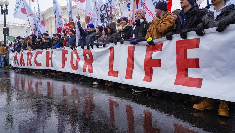 People holding the March for Life banner pause as they march past the Supreme Court on Friday, Jan. 19, 2024, in Washington.