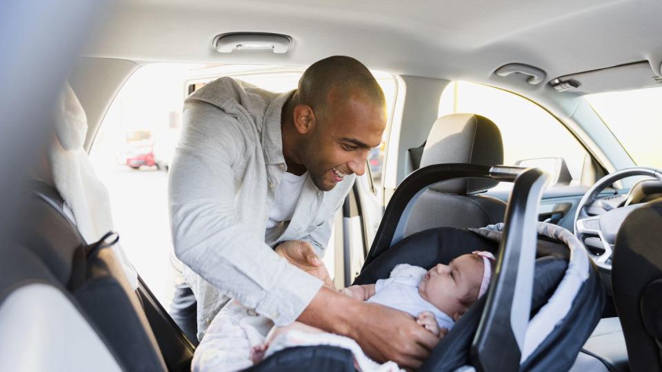 dad putting baby in car seat in car