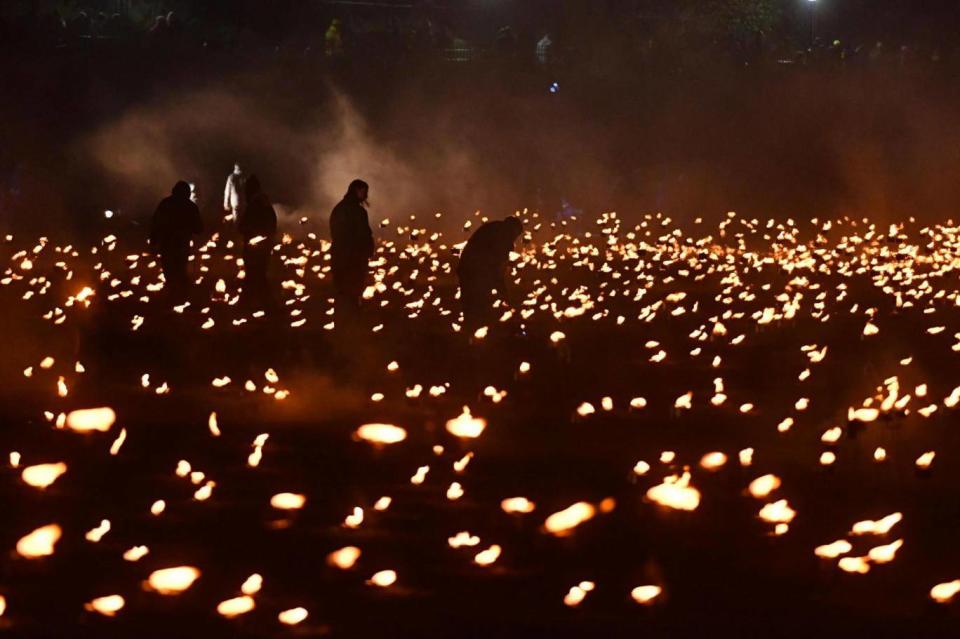 Volunteers help to light thousands of flames in the dry moat of the Tower of London as part of an installation called Beyond the Deepening Shadow: The Tower Remembers (John Stillwell/PA)