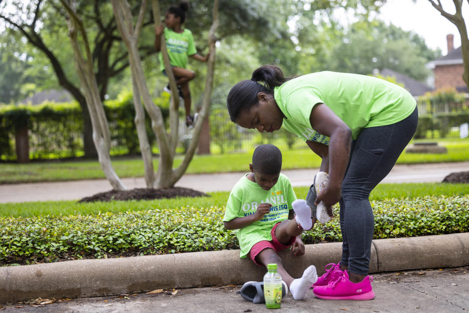School board trustee hopeful Orjanel Lewis helps her five-year-old son Marcus with his shoes outside of the Commonwealth Clubhouse while campaigned for votes on Election Day on May 7, 2022, in Ft. Bend County, Texas. (Annie Mulligan for NBC News)