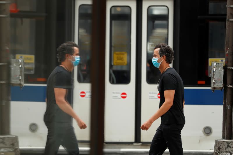 Pedestrians wearing masks walk down the sidewalk in the Manhattan borough of New York City