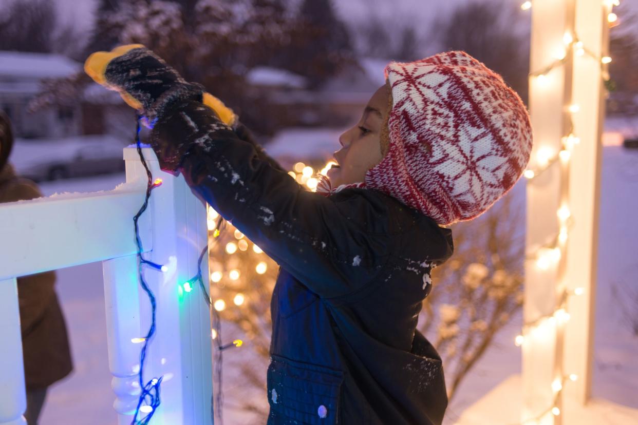 young boy hanging christmas lights