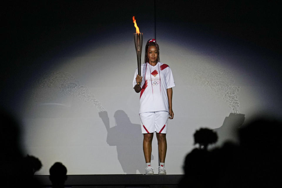 FILE - In this July 23, 2021 file photo, Japan's Naomi Osaka holds the Olympic torch during the opening ceremony in the Olympic Stadium at the 2020 Summer Olympics, in Tokyo, Japan. Osaka and Simone Biles are prominent young Black women under the pressure of a global Olympic spotlight that few human beings ever face. But being a young Black woman -- which, in American life, comes with its own built-in pressure to perform -- entails much more than meets the eye. (AP Photo/Natacha Pisarenko, File)