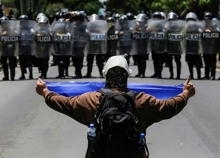 A masked demonstrator shows a Nicaraguan flag to a line of riot police blocking a street during a protest against Nicaraguan President Daniel Ortega's government in Managua, on September 16, 2018