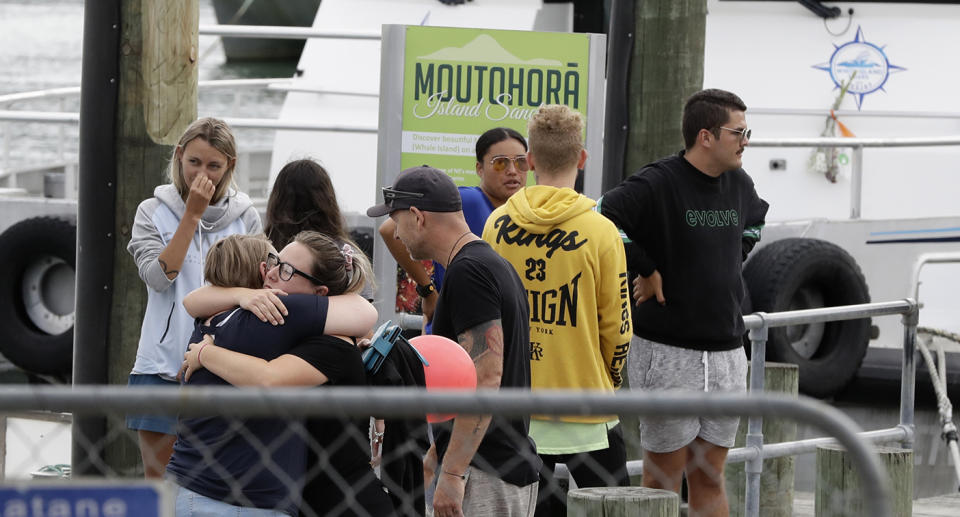Families of victims of the White Island eruption embrace as they arrive back to the Whakatane wharf following a blessing at sea ahead of the recovery operation off the coast of Whakatane New Zealand, Friday, Dec. 13, 2019. A team of eight New Zealand military specialists landed on White Island early Friday to retrieve the bodies of victims after the Dec. 9 eruption. (AP Photo/Mark Baker)