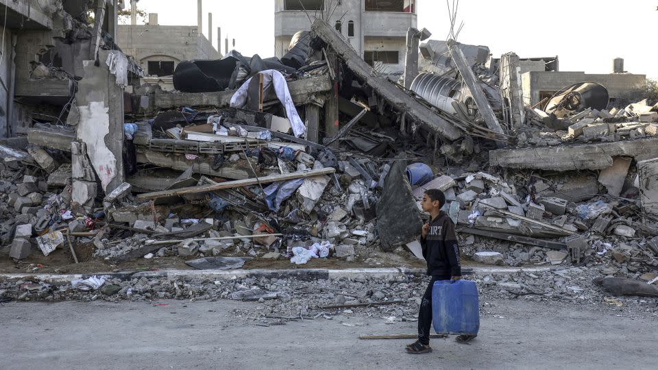 A Palestinian boy carrying water walks past a destroyed house in Rafah, October 18, 2023. - Abed Rahim Khatib/picture-alliance/dpa/AP