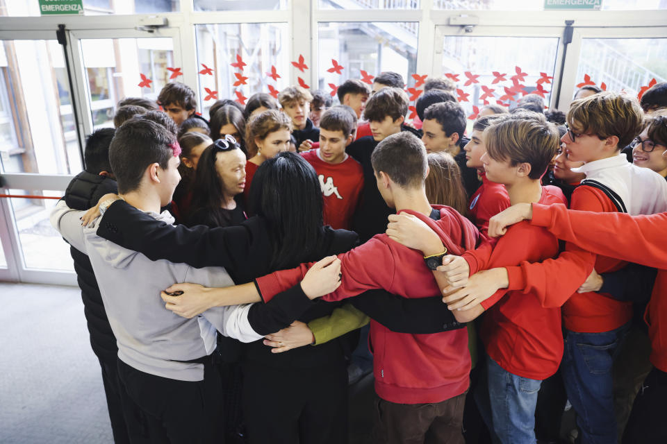 Valentina Pitzalis, second from left, a survivor of a killing attempt by her ex-husband speaks with a group of students during a flash mob in memory of Giulia Cecchettin, allegedly killed at the hands of her possessive ex-boyfriend at the Vittorini High School in Milan, Monday Nov. 21, 2023. Outrage over violence against women is mounting in Italy, with students leading the way. Young people across the country have taken to pounding on classroom desks in unison to demand an end to the slayings of women by men and to root out corrosive, patriarchal attitudes that have long been a part of Italian society. (Alessandro Bremec/LaPresse via AP)