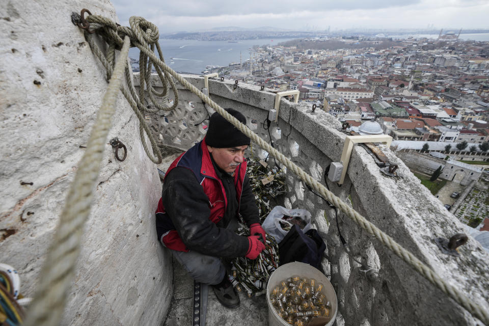 Mahya master Cemil Buyurkan works in the installation of a lights message at the top of one of the minarets of the Suleymaniye Mosque in Istanbul, Turkey, Wednesday, March 6, 2024. Mahya is the unique Turkish tradition of stringing religious messages and designs between minarets. (AP Photo/Emrah Gurel)