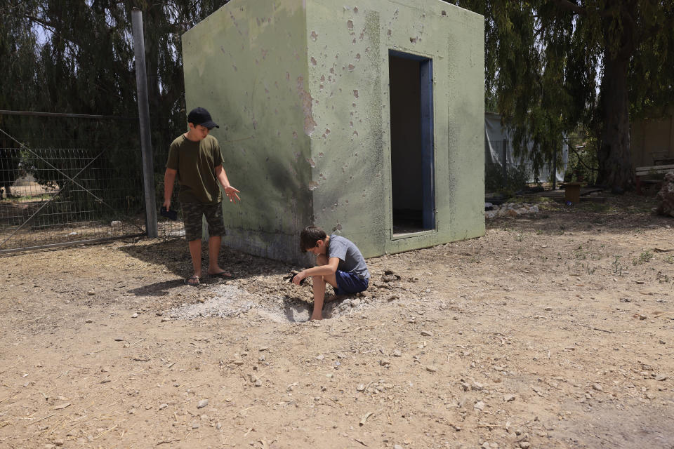 Israeli boys examine the site where a rocket fired from the Gaza Strip landed in Israel, Saturday, April 24, 2021. Palestinian militants in the Gaza Strip fired some three dozen rockets into Israel overnight Saturday, while the Israeli military struck back at targets operated by the ruling Hamas group.(AP Photo/Tsafrir Abayov)