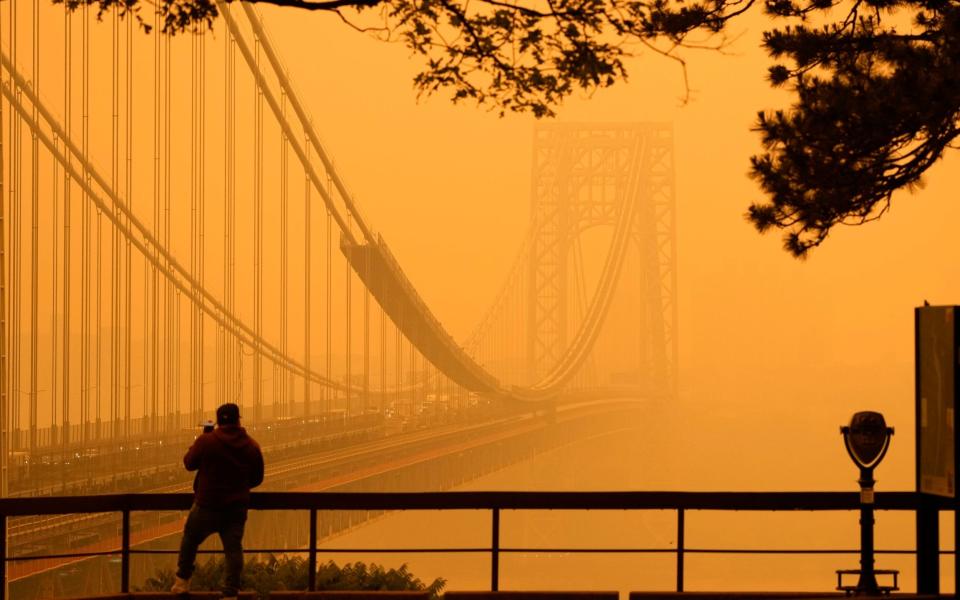 A man talks on his phone as he looks through the haze at the George Washington Bridge from Englewood Cliffs - Seth Wenig/AP