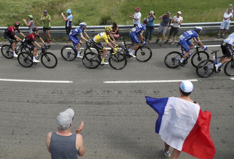 Spectators, one with a French flag cheer the riders with France's Julian Alaphilippe wearing the overall leader's yellow jersey during the ninth stage of the Tour de France cycling race over 170.5 kilometers (105.94 miles) with start in Saint Etienne and finish in Brioude, France, Sunday, July 14, 2019. (AP Photo/Thibault Camus)