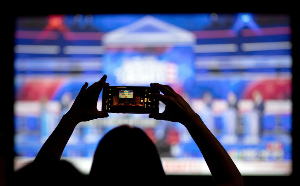 FILE - In this June 27, 2019, file photo, a woman takes a photo of the television while watching a Democratic presidential debate at a watch party in Atlanta. The Democratic race for the White House has been marked by online infighting and unsubstantiated allegations of election rigging. (AP Photo/David Goldman, File)