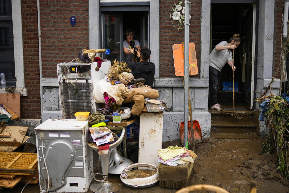 People pass damaged belongings out of a house after flooding in Ensival, Verviers, Belgium, Friday July 16, 2021. Severe flooding in Germany and Belgium has turned streams and streets into raging torrents that have swept away cars and caused houses to collapse. (AP Photo/Francisco Seco)