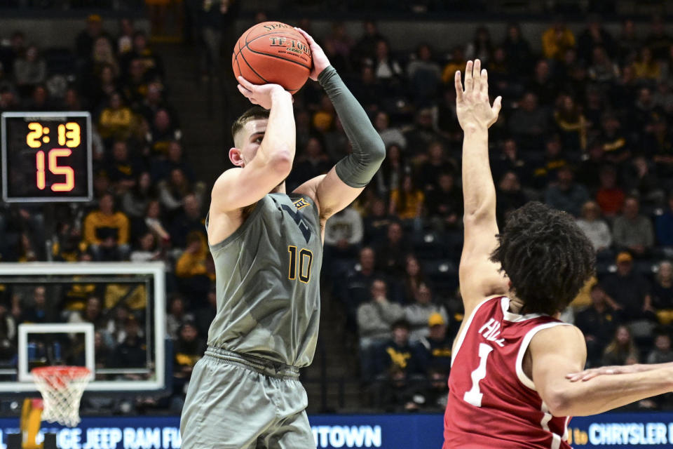 West Virginia guard Erik Stevenson (10) makes a three point basket while being guarded by Oklahoma forward Jalen Hill (1) during the first half of an NCAA college basketball game in Morgantown, W.Va., Saturday, Feb. 4, 2023. (AP Photo/William Wotring)