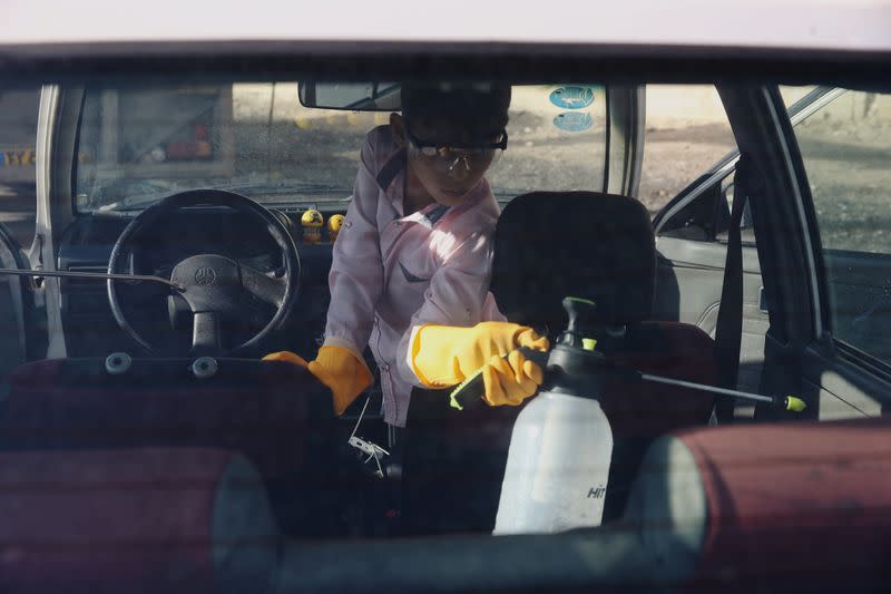 A volunteer wearing protective gloves, following the outbreak of coronavirus disease (COVID-19), disinfects a car in Qom