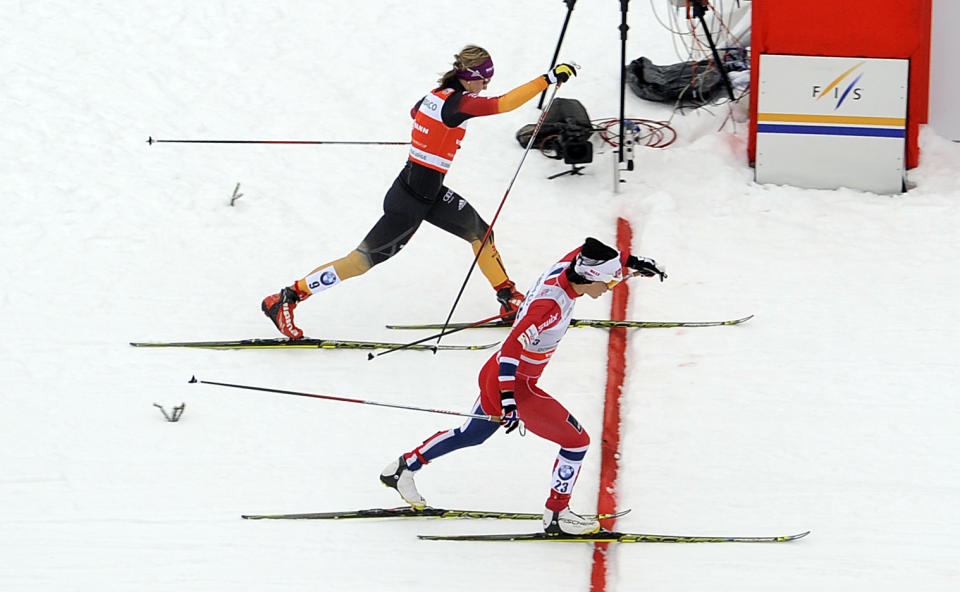Second placed Denise Herrmann of Germany, left, and winner Marit Bjoergen of Norway, cross the finish line of a cross country women's World Cup sprint, in Dobbiaco, Italy, Sunday, Feb. 2, 2014. (AP Photo/Elvis Piazzi)