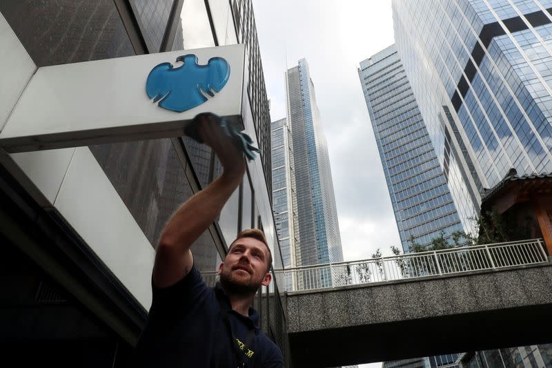 FILE PHOTO: A worker cleans a Barclays logo outside a bank branch in the financial district of London