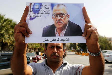 A relative of the Jordanian writer Nahed Hattar holds his picture during a sit-in in the town of Al-Fuheis near Amman, Jordan, September 25, 2016. REUTERS/Muhammad Hamed