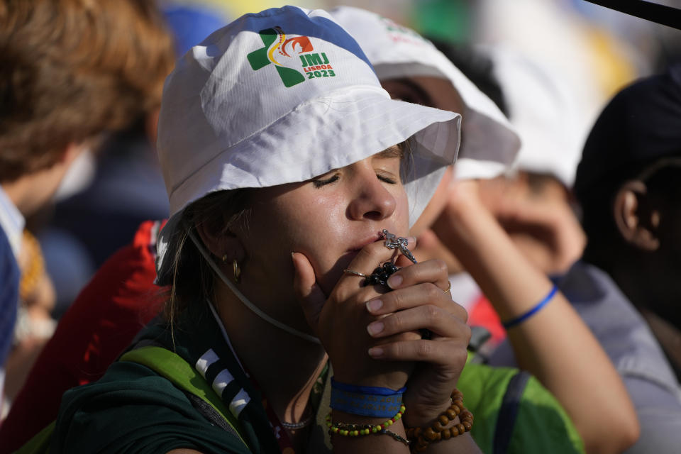 A pilgrim kisses a crucifix while Pope Francis presides over a via crucis (Way of the Cross) at the Eduardo VII Park with young people in Lisbon, Friday, Aug. 4, 2023. Pope Francis is on the third day of a five-day pastoral visit to Portugal that includes the participation at the 37th World Youth Day, and a pilgrimage to the holy shrine of Fatima. (AP Photo/Gregorio Borgia)