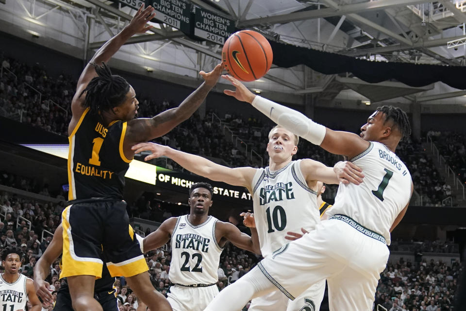 Iowa guard Ahron Ulis (1), Michigan State forward Joey Hauser (10) and guard Pierre Brooks (1) reach for the rebound during the first half of an NCAA college basketball game, Thursday, Jan. 26, 2023, in East Lansing, Mich. (AP Photo/Carlos Osorio)