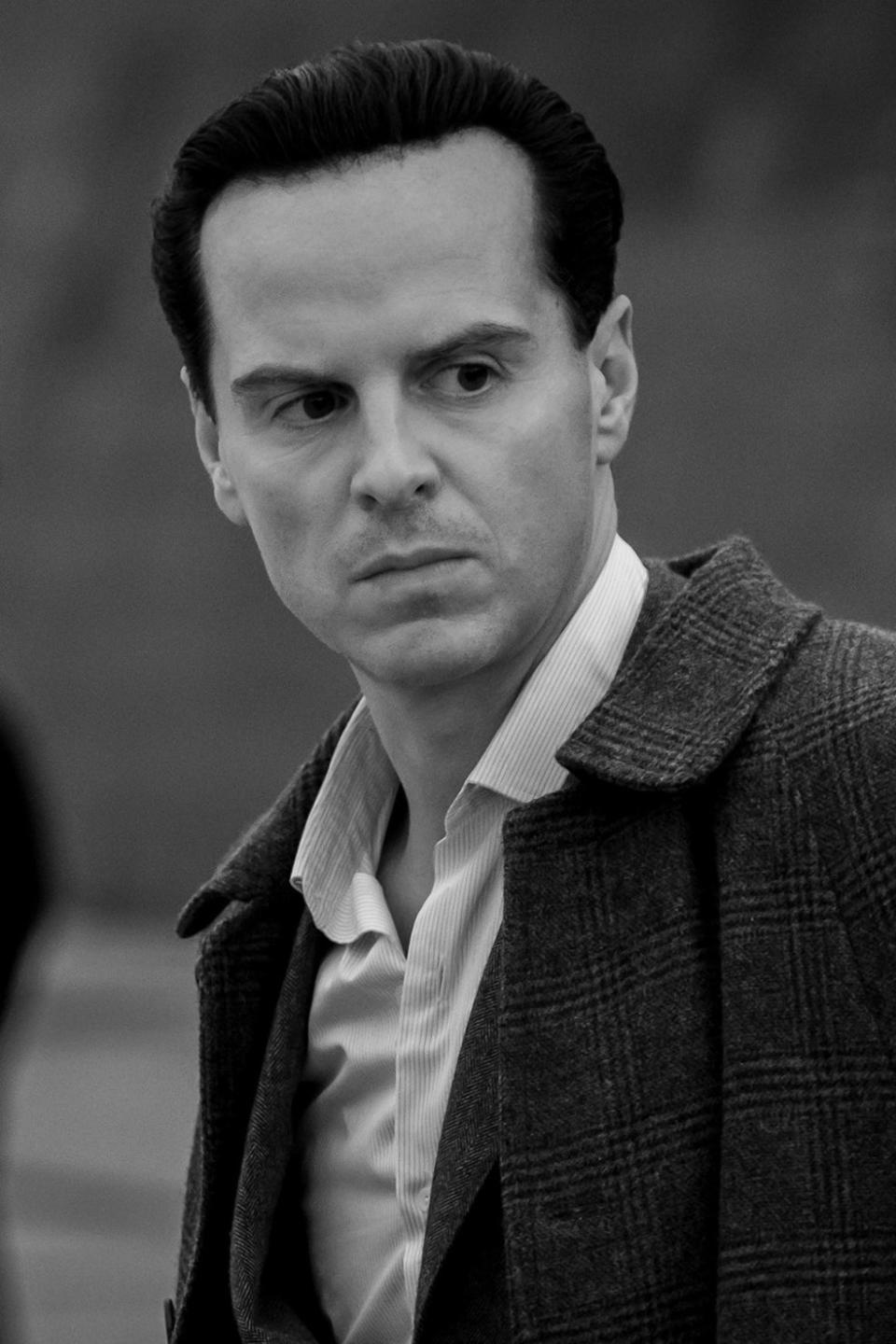 Andrew Scott, wearing a classic blazer, stands in the foreground looking serious, with two uniformed officers and a vintage car blurred in the background