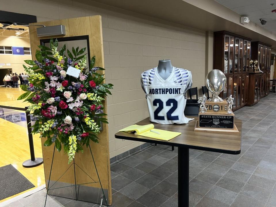 Flowers, a jersey and the 2015 state runner-up trophy outside the Northpoint gym on Tuesday night during the vigil for Christian Saulsberry.