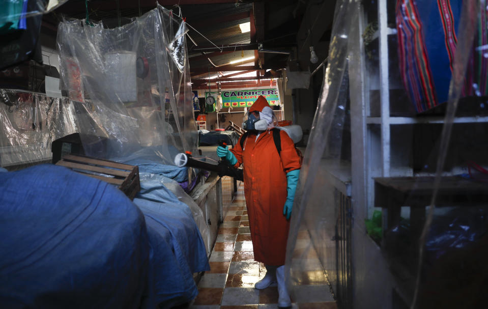 Un trabajador de la ciudad con equipo de protección completo en medio de la nueva pandemia de coronavirus desinfecta el mercado de Haití en La Paz, Bolivia, el martes 23 de junio de 2020. (AP Foto/Juan Karita)