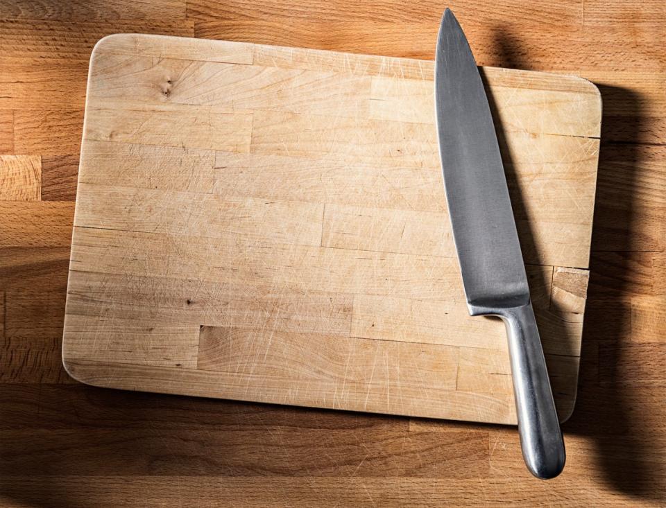 Stainless steel knife on cutting board on top of woodblock counter