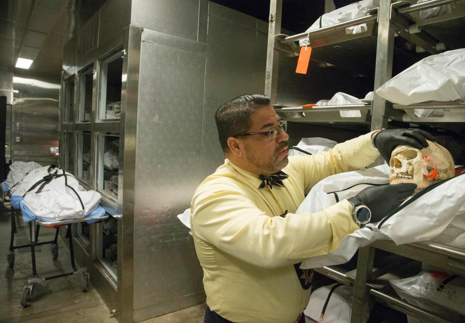 Gene Hernandez, a death investigator supervisor, examines a set of unidentified remains in a cooler at the Pima County Medical Examiner Office in Tucson, Ariz. When migrants die in the Arizona desert, their body or remains are brought here for DNA identification. Mandatory Credit: Nick Oza/The Arizona Republic via USA TODAY NETWORK [Via MerlinFTP Drop]