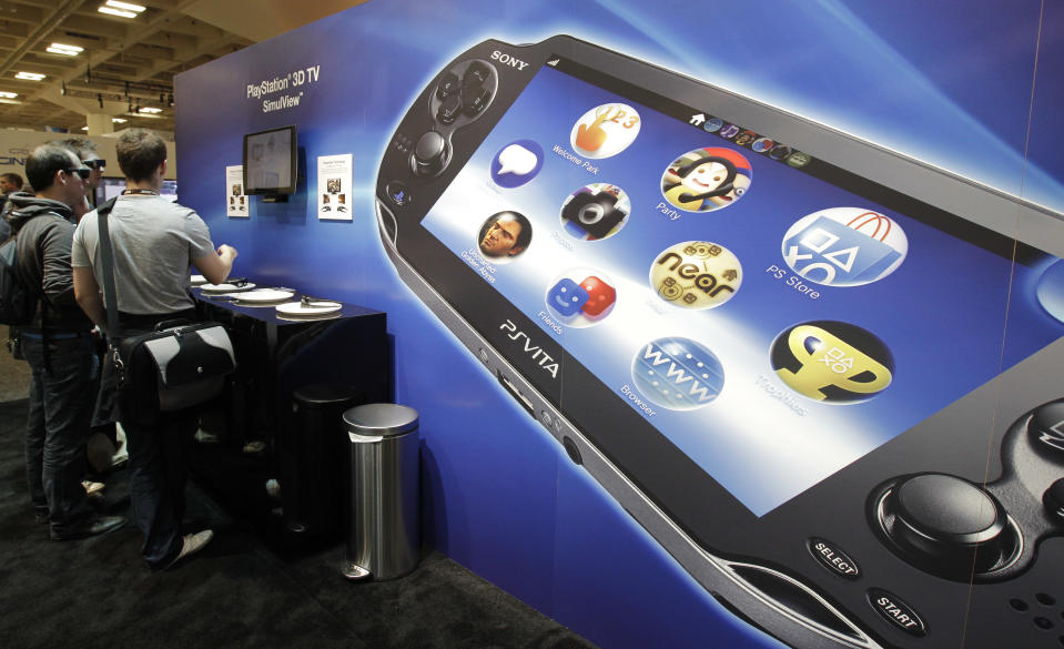 Sony PlayStation PS Vita is shown in foreground as attendees use the Sony PlayStation 3D TV SimuView in the Sony PlayStation booth at the Game Developers Conference in San Francisco, Thursday, March 8, 2012. (AP Photo/Paul Sakuma)