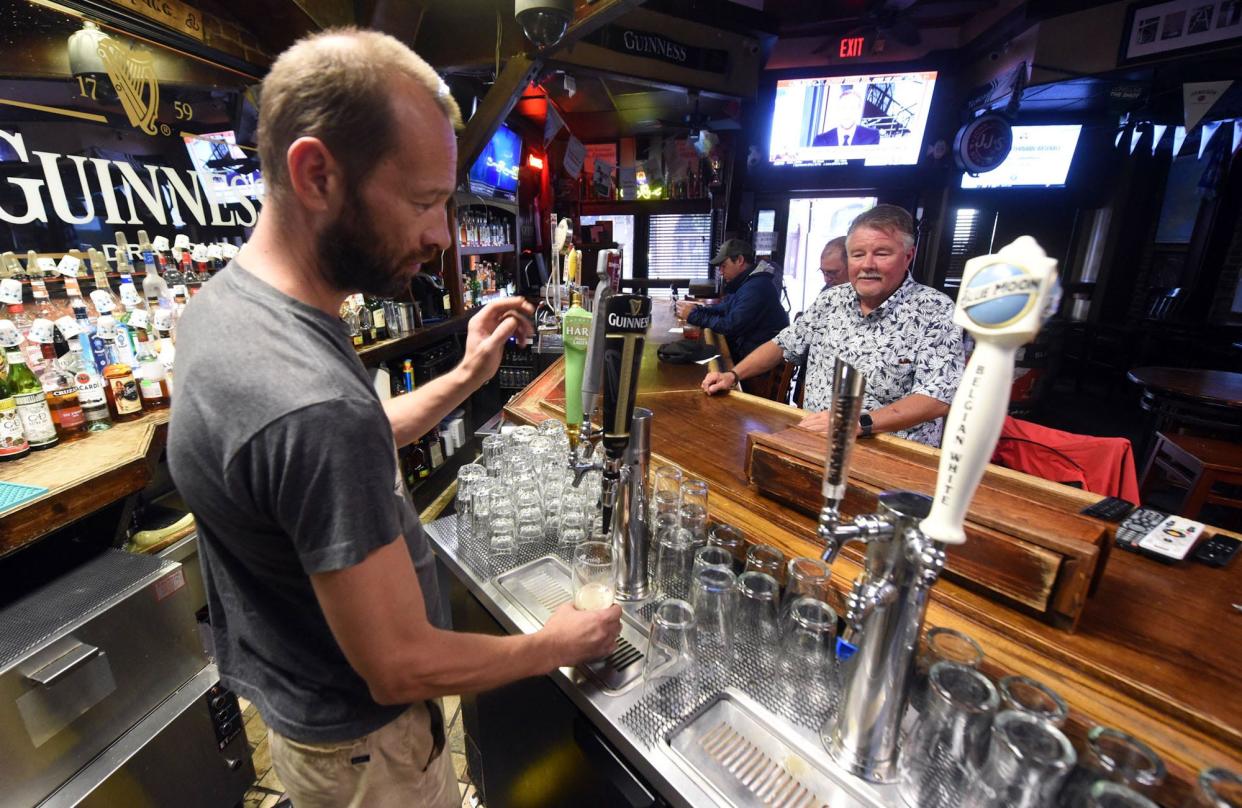 Slainte co-owner Misha Sobol serves a beer at his bar in downtown Wilmington in 2019.