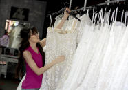 In this Friday, June 21, 2019, photo Assistant manager Brooke Hernandez hangs wedding gowns Friday, June 21, 2019 at Strut Bridal Shop in Tempe, Ariz. Cut-rate prices on websites that sell wedding dresses direct from China put pressure on owner Ann Campeau, who owns four bridal shops in California and Arizona. She has had customers come in after seeing low-end gowns online and expecting to get a dress at a similar price. (AP Photo/Matt York)