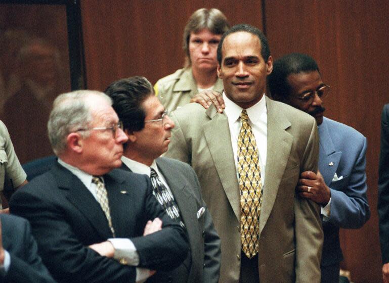 Attorney Johnnie Cochran Jr. holds onto O.J. Simpson as the not guilty verdict is read in a Los Angeles courtroom Tuesday morning, Oct. 3, 1995. Left is F. Lee Bailey and second from left is Robert Kardashian. (AP Photo/Pool, Myung J. Chun)